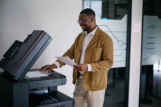 Utilisateur souriant devant un photocopieur multifonction au bureau